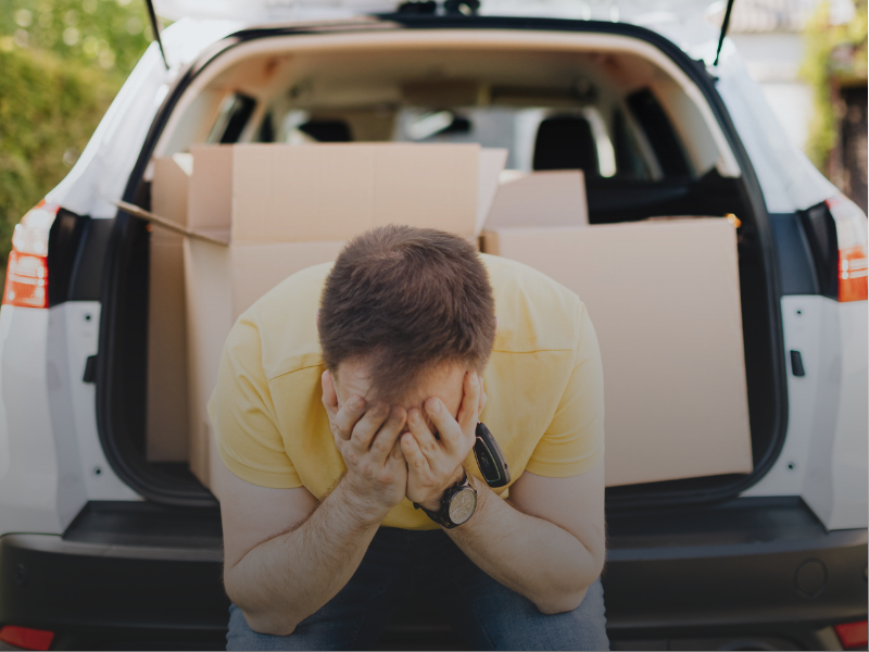 Stressed man covering face while moving out