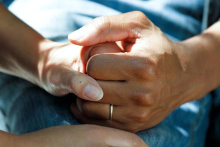 Two people holding hands in comforting manner.